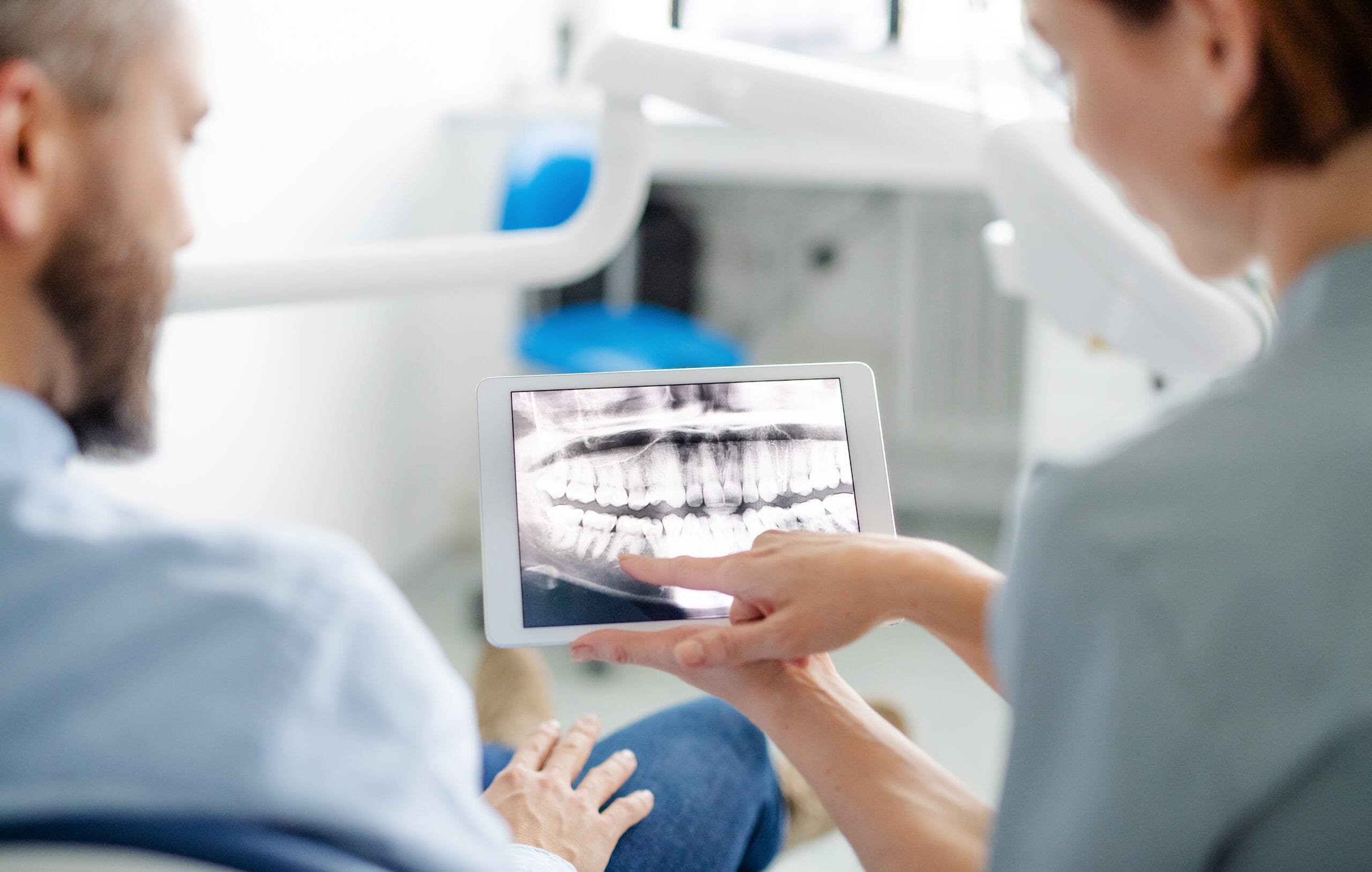 Rear view of man and dentist in dental surgery, annual check-up.